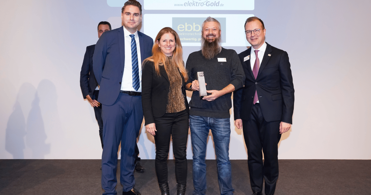 Murml und Christoph Gold von elektro-Gold nehmen die ELMAR-Silber-Auszeichnung entgegen. Sie stehen gemeinsam mit Vertreter*innen der Elektromarken. Starke Partner. auf der Bühne.