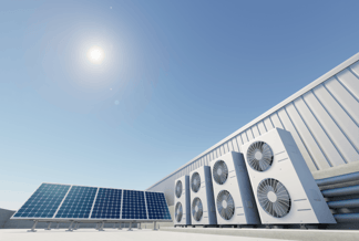 Photovoltaik-Panels und Wärmepumpen auf einem Flachdach, darüber blauer Himmel und Sonne