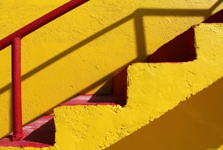 4 Stufen einer gelben Betontreppe mit roten Stufen und Geländer; Bild fotografiert von Mahdis Mousavi
