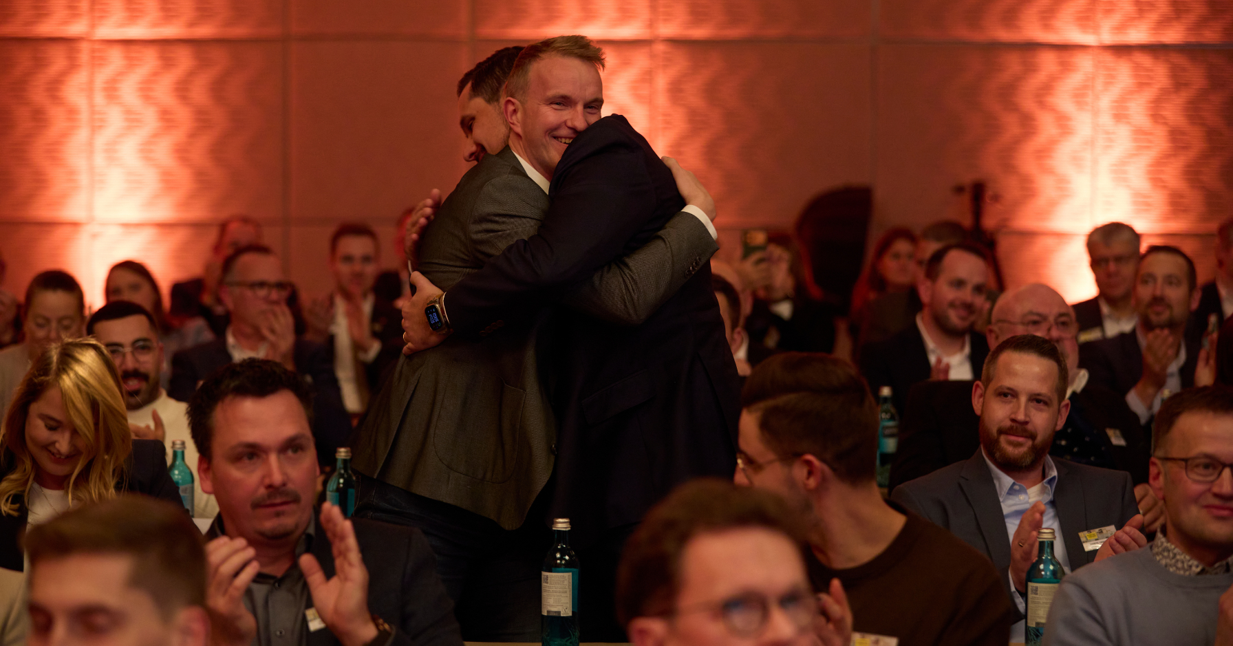 Zwei Männer umarmen sich mitten im applaudierenden Publikum beim Markenforum 2025 – der emotionale Moment der ELMAR Newcomer Preisverleihung an die LuPa Sonnenenergie GmbH aus Höxter.
